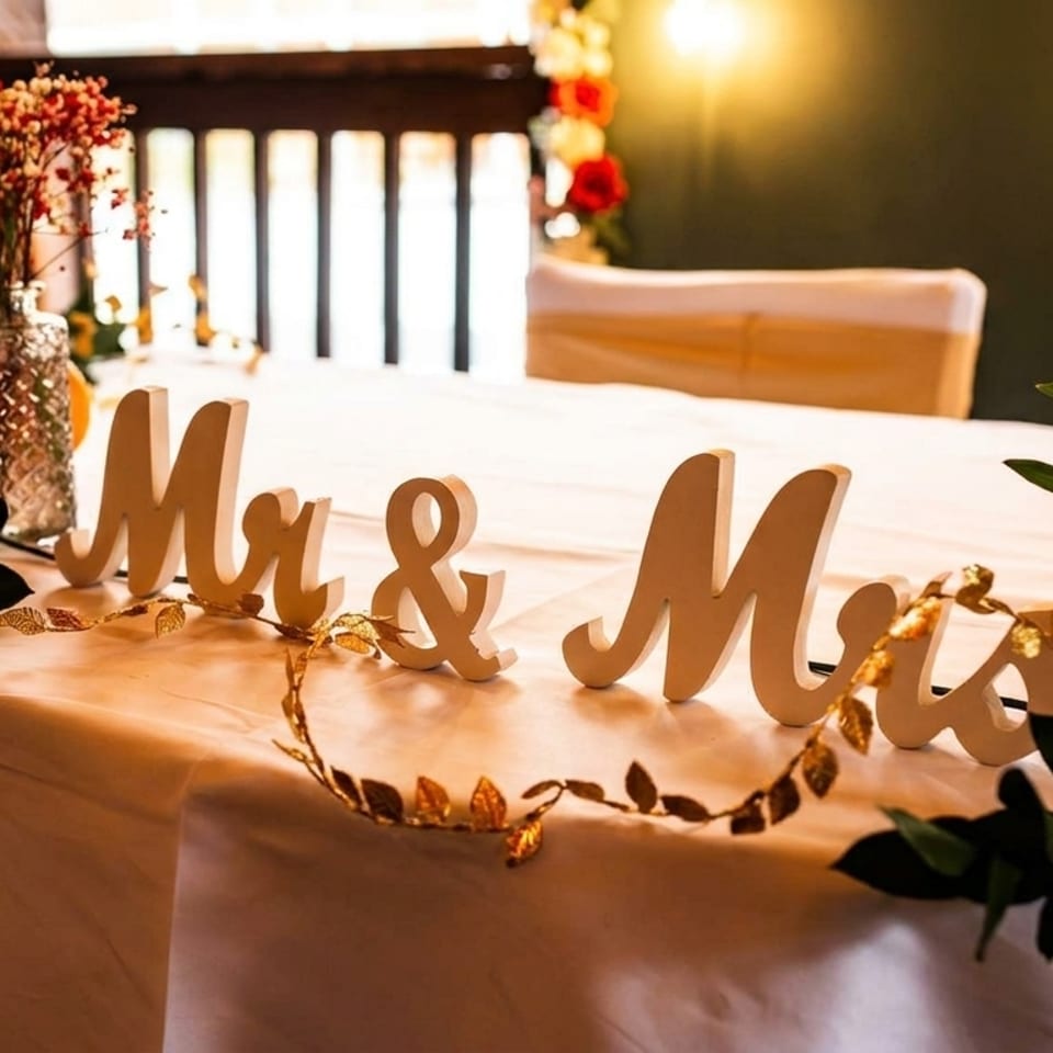 A white tablecloth with "Mr & Mrs" signs, floral arrangements, and small pumpkins.